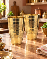 Front view of two engraved brass tumblers in a heritage kitchen setting