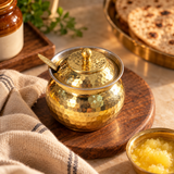 Hammered Brass Ghee Pot with Lid and Spoon wooden board lifestyle image