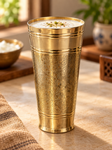 Engraved brass tumbler filled with lassi in warm home setting