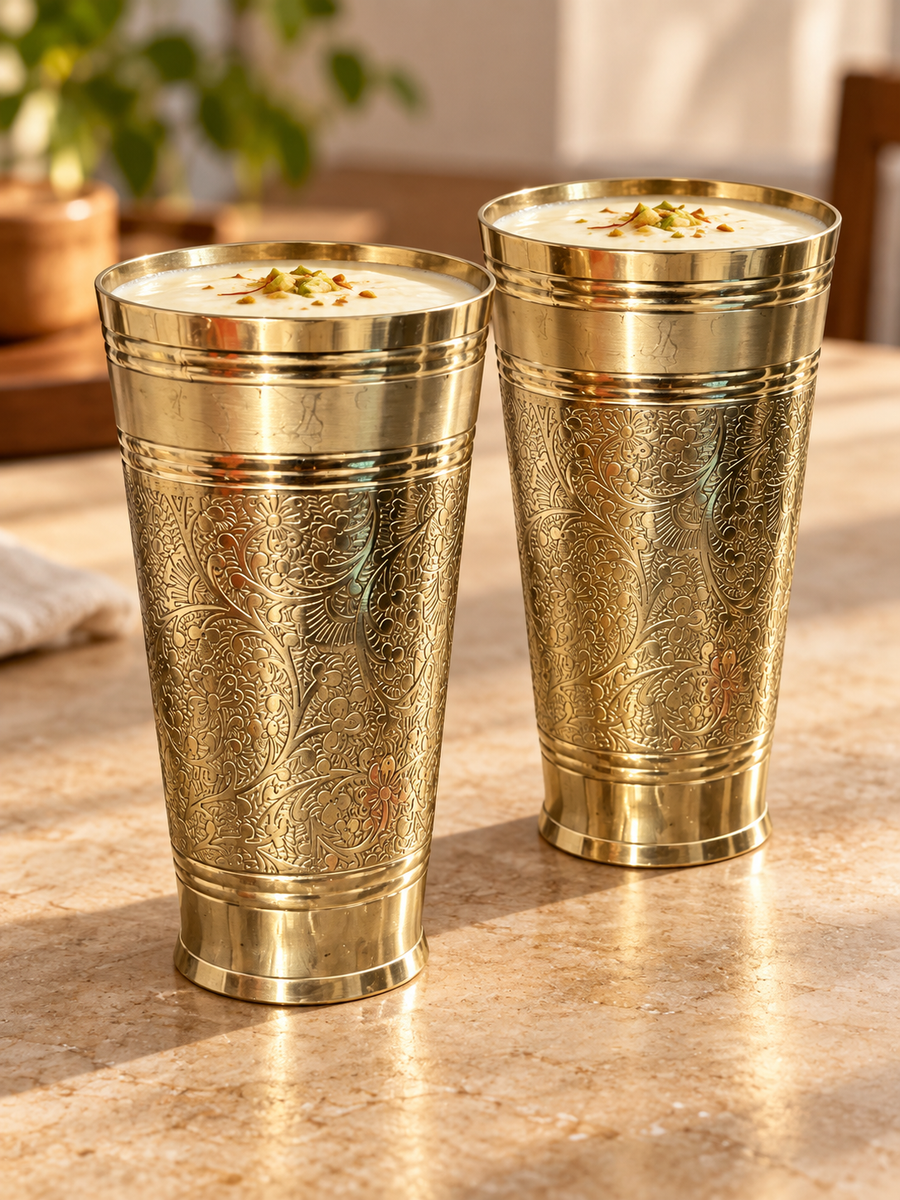 Pair of engraved brass tumblers filled with lassi