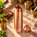 Top-angle view of hammered copper water bottle with open lid and water