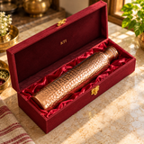 Hammered copper water bottle resting inside its maroon satin-lined gift box
