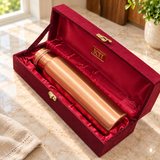 Slim brushed copper water bottle resting inside its red satin lined maroon gift box
