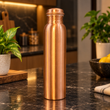 Slim plain copper water bottle with ringed cap in a warm premium kitchen