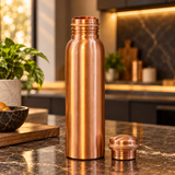 Slim copper water bottle with cap beside it on a premium countertop
