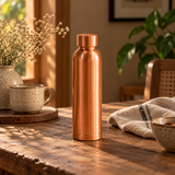 Plain copper water bottle matte finish on rustic wooden table in warm home setting